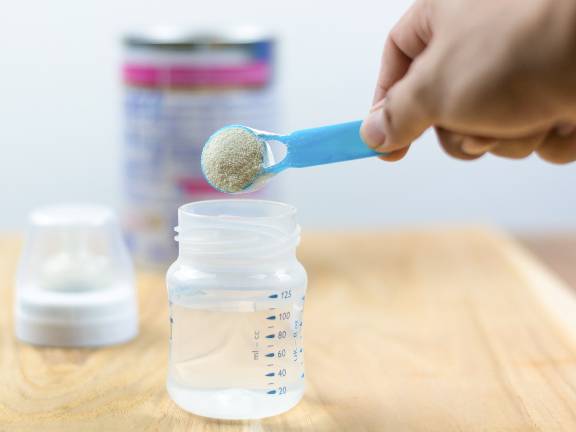 Baby formula being scooped into a bottle