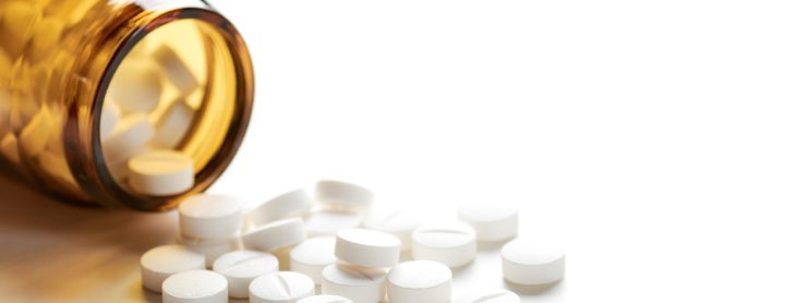 Bottle with aspirin pills on table