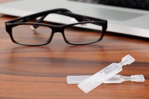 Dry eye drops, glasses and laptop