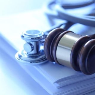 Gavel and stethoscope on stack of papers