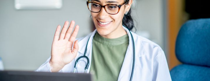 Doctor waves at laptop screen
