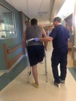 Tim Hopkins on crutches with physical therapist
