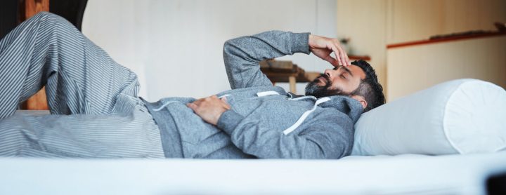 Man lying down in bed while in pain