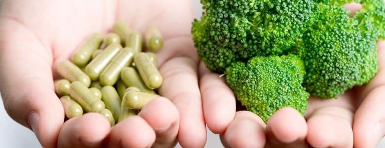 person holding pills and broccoli