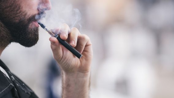 Man vaping from an e-cigarette device