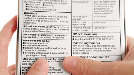 Person reading drug label on back of box