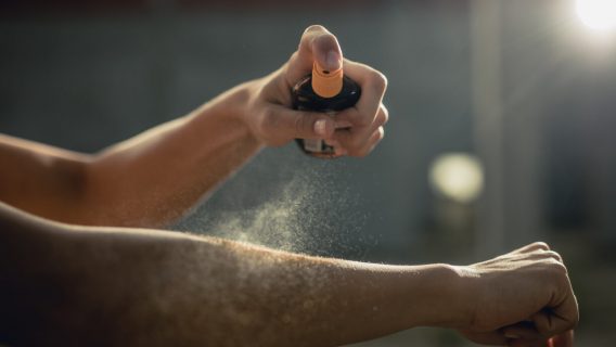 Woman spraying aerosol sunscreen on her arm