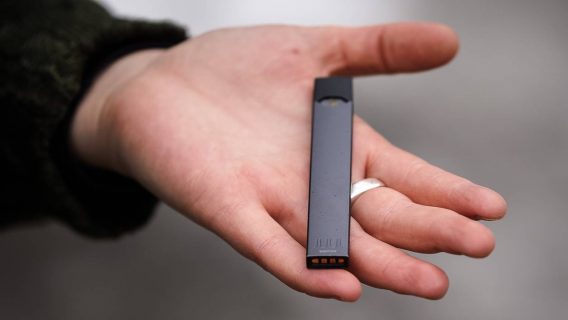 A woman is holding a Juul e-cigarette