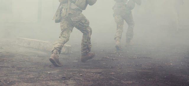 Army soldiers running in smoke during combat