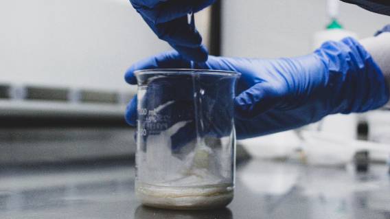 Pharmacist with blue gloves and glass jar