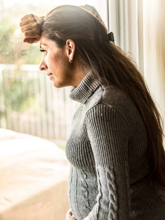 concerned pregnant woman looking out window