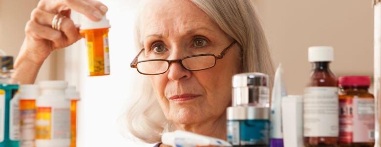 elderly lady looking at prescription bottles