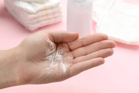 Talcum powder in woman's hand, diapers