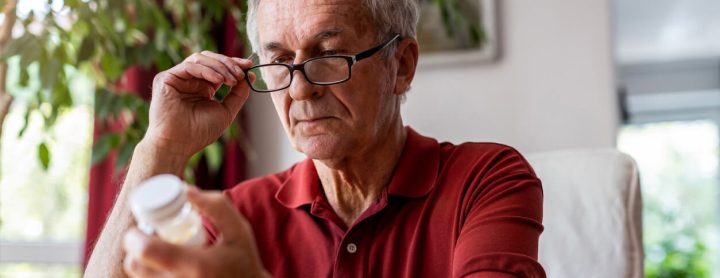 Elderly man reading his prescription pill label