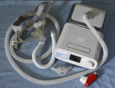 Recalled CPAP device on a blue sheet with an inhaler next to it